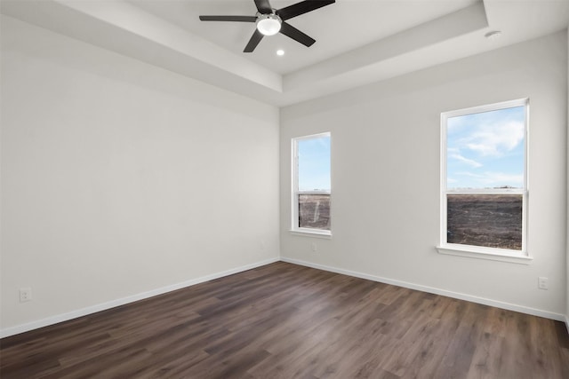 spare room featuring ceiling fan, dark hardwood / wood-style flooring, and a raised ceiling