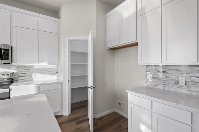 kitchen featuring light stone counters, backsplash, white cabinetry, and dark hardwood / wood-style floors