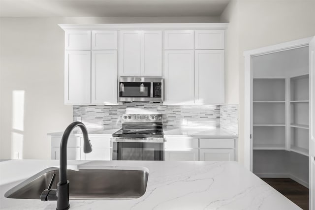 kitchen with white cabinets, decorative backsplash, sink, and stainless steel appliances