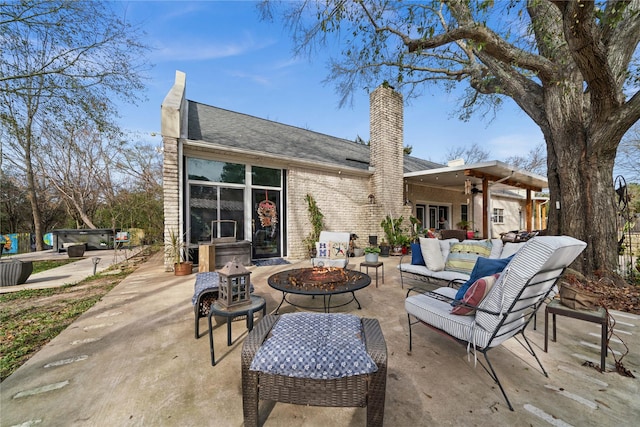 rear view of property featuring ceiling fan, an outdoor living space with a fire pit, and a patio area