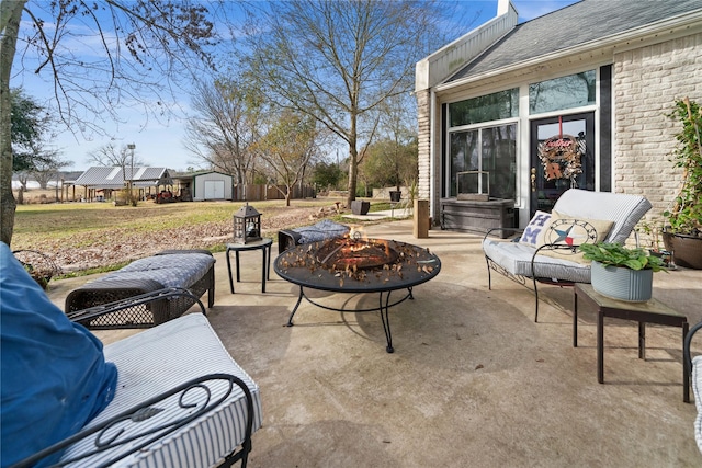 view of patio / terrace featuring an outdoor fire pit and a storage shed