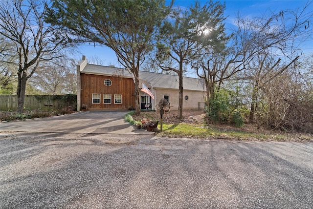 view of front of house with driveway, fence, and a chimney