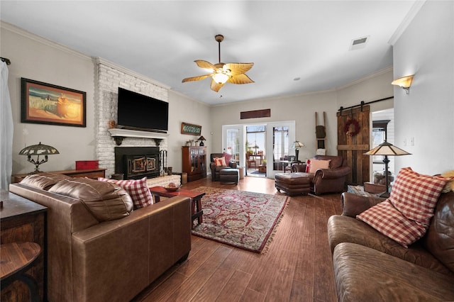 living room featuring ceiling fan, a barn door, crown molding, and hardwood / wood-style floors