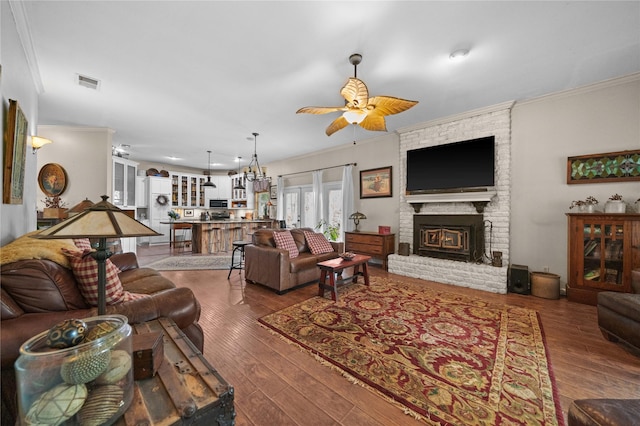 living room with ceiling fan, crown molding, hardwood / wood-style flooring, and a brick fireplace