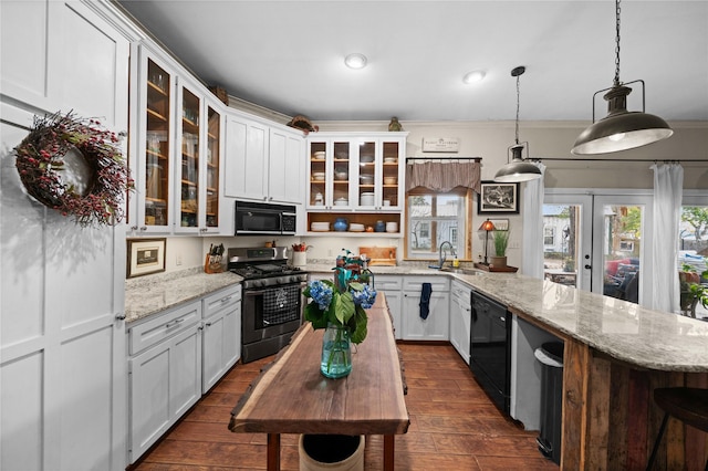 kitchen featuring black appliances, light stone counters, sink, and hanging light fixtures