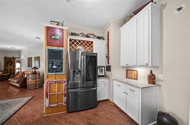 kitchen featuring ornamental molding, white cabinets, stainless steel fridge, and a barn door