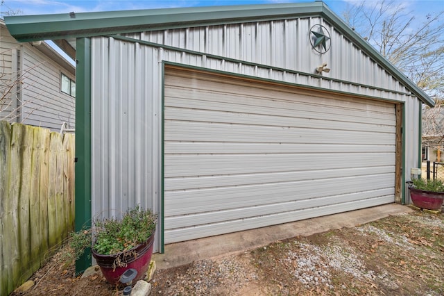 detached garage featuring fence and dirt driveway