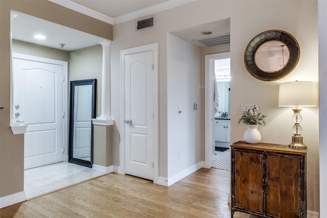 corridor with decorative columns, light hardwood / wood-style floors, and crown molding