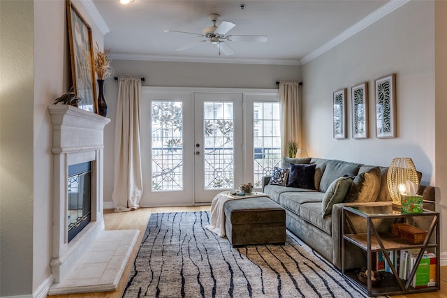 living room featuring light hardwood / wood-style flooring, french doors, ceiling fan, a tile fireplace, and crown molding