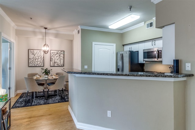 kitchen with crown molding, stainless steel appliances, pendant lighting, and kitchen peninsula