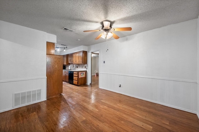 unfurnished living room featuring light hardwood / wood-style floors, a textured ceiling, and ceiling fan