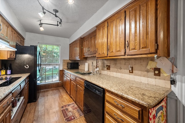 kitchen with decorative backsplash, track lighting, light hardwood / wood-style flooring, light stone counters, and black appliances