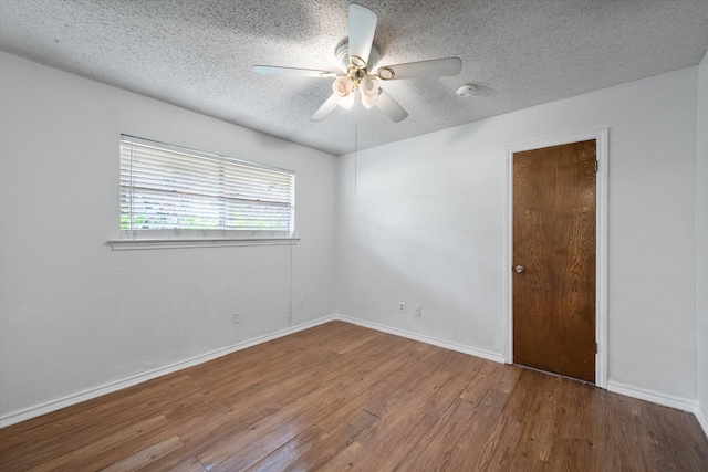 empty room with ceiling fan, wood-type flooring, and a textured ceiling