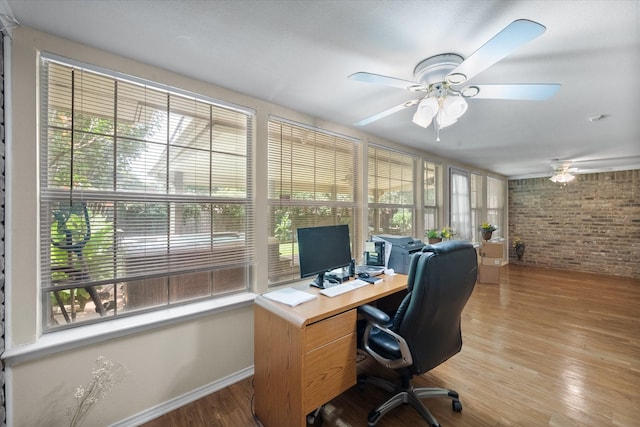 home office with ceiling fan, brick wall, and hardwood / wood-style floors