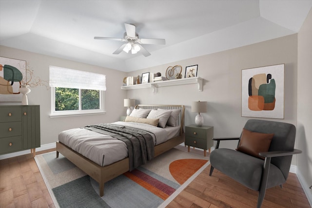 bedroom featuring ceiling fan, hardwood / wood-style floors, and a raised ceiling