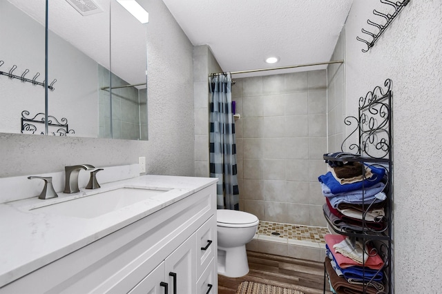 bathroom with toilet, vanity, a shower with shower curtain, and a textured ceiling