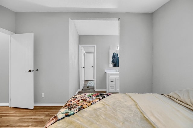 bedroom with connected bathroom and wood-type flooring