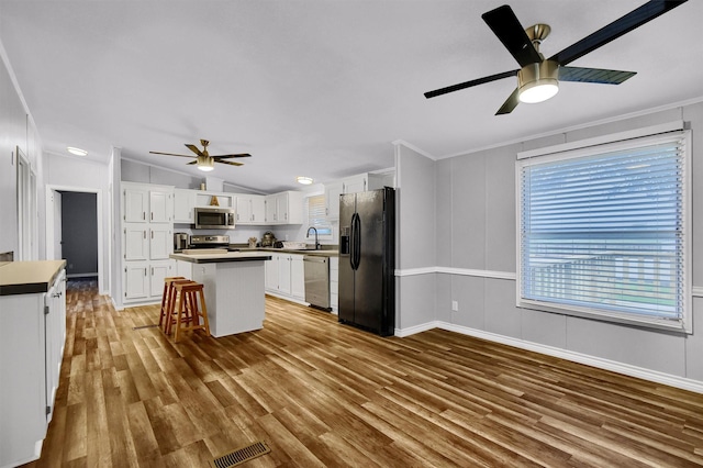 kitchen featuring white cabinets, a kitchen island, stainless steel appliances, sink, and vaulted ceiling