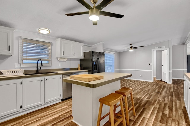 kitchen with a kitchen breakfast bar, white cabinetry, black fridge, and a kitchen island