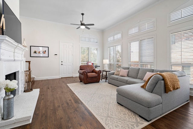 living room with ceiling fan, dark hardwood / wood-style flooring, ornamental molding, and a fireplace