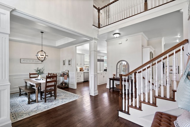 foyer featuring dark wood-type flooring, ornate columns, and a chandelier