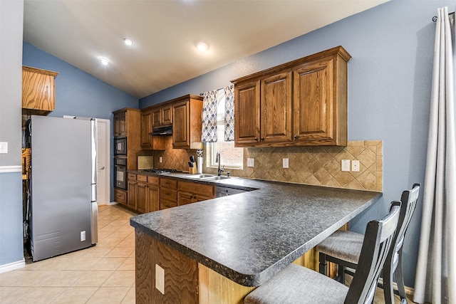 kitchen with black appliances, sink, kitchen peninsula, vaulted ceiling, and a breakfast bar