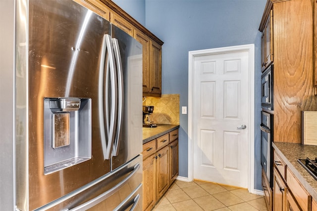 kitchen featuring backsplash, dark stone countertops, stainless steel appliances, and light tile patterned flooring