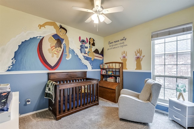 bedroom with ceiling fan, a nursery area, and carpet