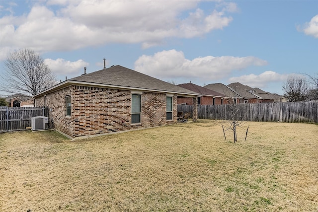 rear view of house with cooling unit and a lawn