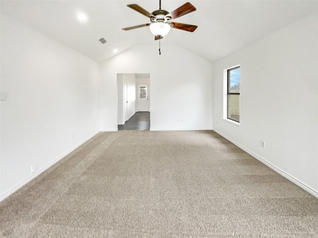 empty room featuring vaulted ceiling, dark carpet, and ceiling fan