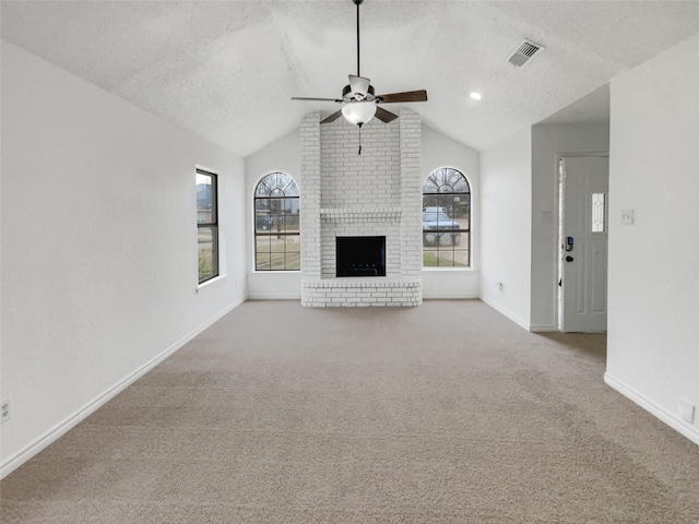 unfurnished living room with a brick fireplace, a textured ceiling, lofted ceiling, and a healthy amount of sunlight