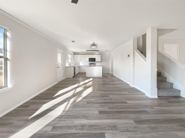 unfurnished living room featuring sink, ornamental molding, and dark hardwood / wood-style floors