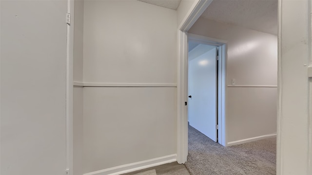 corridor with a textured ceiling and carpet floors