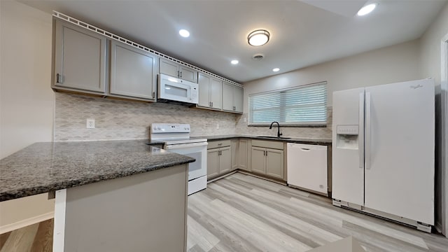 kitchen with kitchen peninsula, sink, white appliances, light wood-type flooring, and gray cabinetry