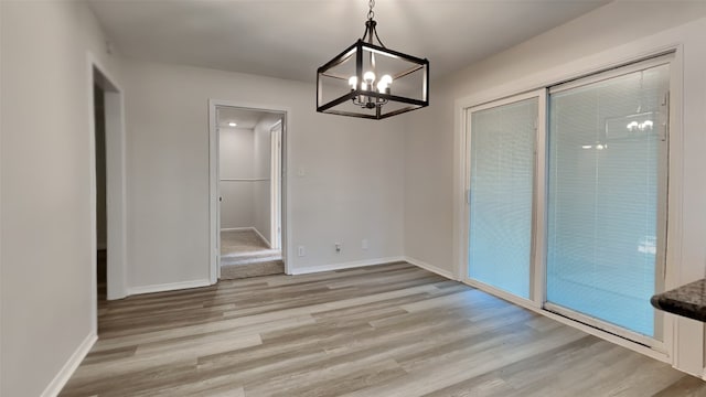 unfurnished dining area featuring light wood-type flooring and a chandelier