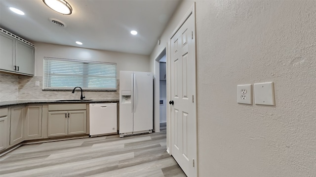 kitchen with gray cabinetry, tasteful backsplash, white appliances, light wood-type flooring, and sink