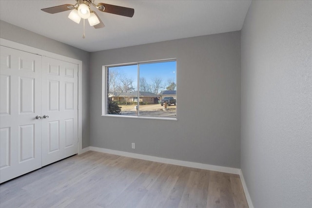 unfurnished bedroom with ceiling fan, a closet, wood finished floors, and baseboards