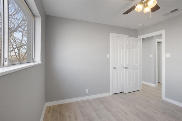 unfurnished bedroom with light wood-style flooring, a ceiling fan, visible vents, baseboards, and a closet