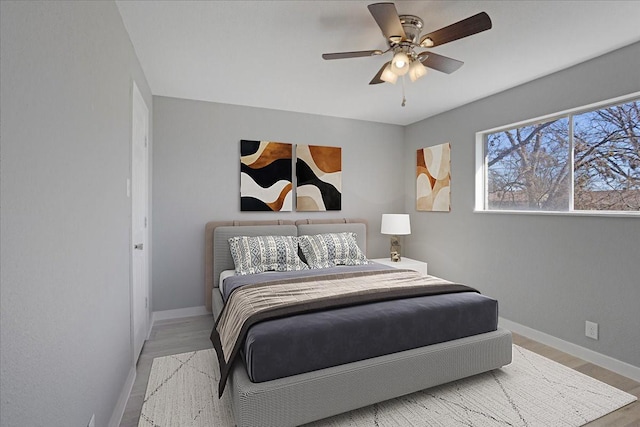 bedroom with light wood-type flooring, ceiling fan, and baseboards