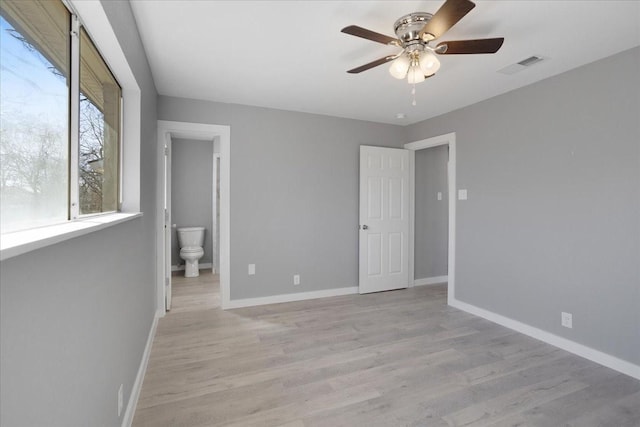 unfurnished room with light wood-type flooring, visible vents, ceiling fan, and baseboards