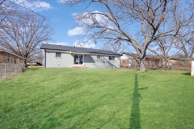 rear view of house with brick siding, a lawn, and fence