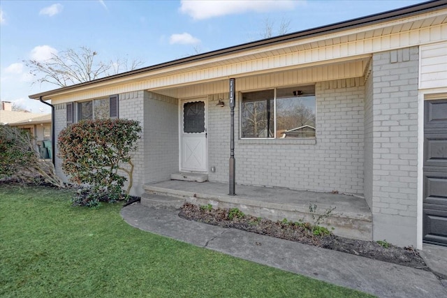 property entrance featuring a yard and brick siding