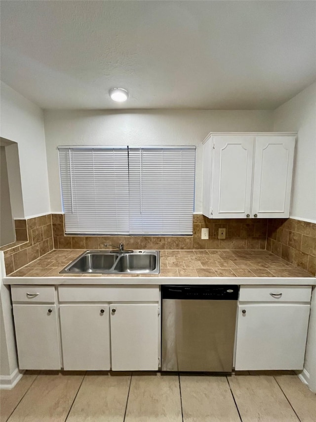 kitchen featuring light tile patterned flooring, tasteful backsplash, white cabinetry, dishwasher, and sink