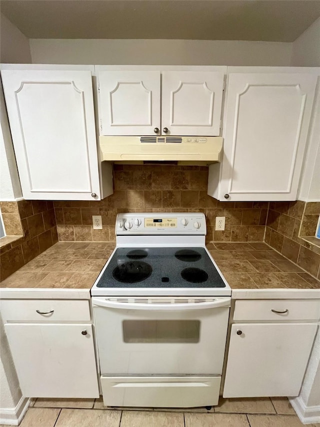 kitchen with tile countertops, white range with electric stovetop, tasteful backsplash, white cabinetry, and light tile patterned floors