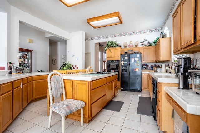 kitchen with black appliances, a kitchen island, kitchen peninsula, tile countertops, and light tile patterned floors