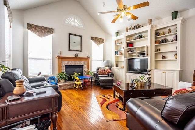 living room with vaulted ceiling, a healthy amount of sunlight, a fireplace, and light hardwood / wood-style flooring