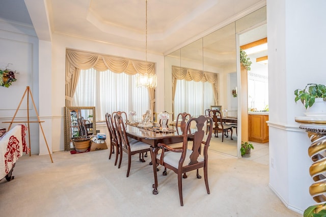 dining room with a healthy amount of sunlight, light colored carpet, and a raised ceiling