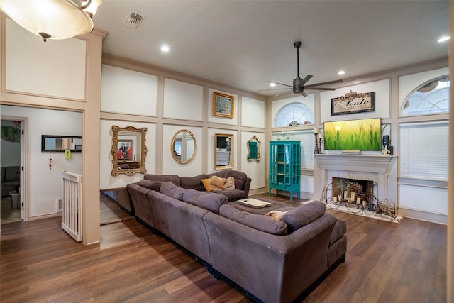 living room with ceiling fan, a tile fireplace, dark hardwood / wood-style flooring, and crown molding