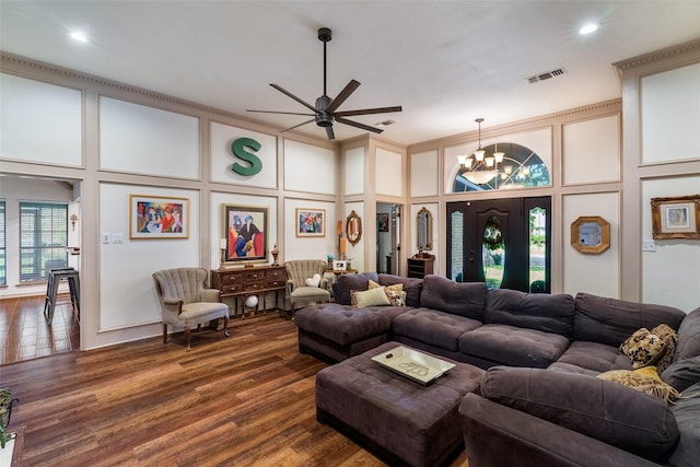 living room with dark hardwood / wood-style floors, ceiling fan with notable chandelier, a towering ceiling, and ornamental molding