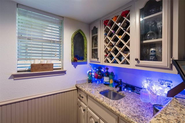 bar featuring light stone countertops and sink